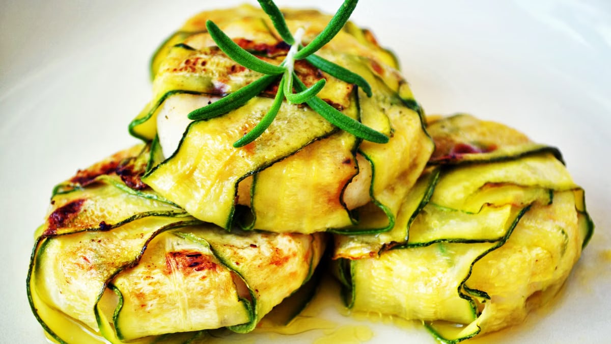 Delicious zucchini wraps stuffed with grilled chicken, presented with fresh rosemary garnish.