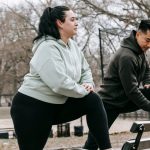 Side view of overweight female in sportswear training with Asian sportsman in activewear in park in daylight